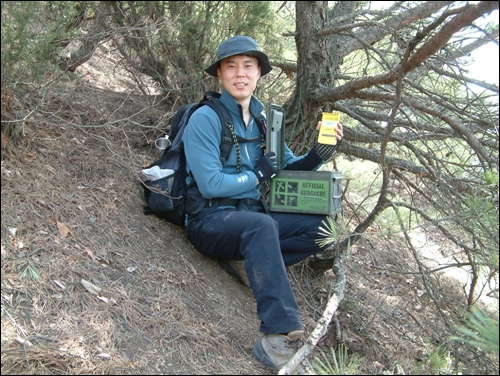 2005년 4월 5일, 한국의 한 지오캐셔가 서울 수락산에 있는 보물을 찾아내고 기뻐하는 모습 / 보물상자는 낡은 탄약통이고, 보물은 여러 가지 기념품으로 채워져 있다 / 이 보물상자를 숨긴 사람은 미군이었는데, 현재는 고향으로 돌아간 상태다 / 이와 관련된 정보는 지오캐싱 공식 홈페이지의 해당 페이지에 기록되어 있다 